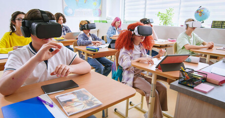 Smart pupils wearing VR headsets and studying with future technologies at classroom. Excited boys...