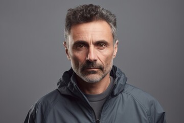 Fototapeta premium Portrait of mature man in jacket looking at camera, on grey background