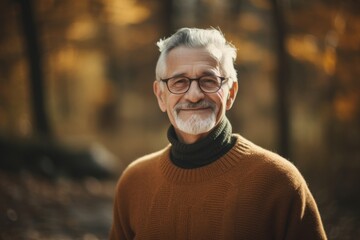 Portrait of a senior man with glasses in the autumn park.