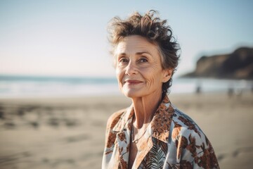 Portrait of smiling senior woman standing on beach and looking at camera