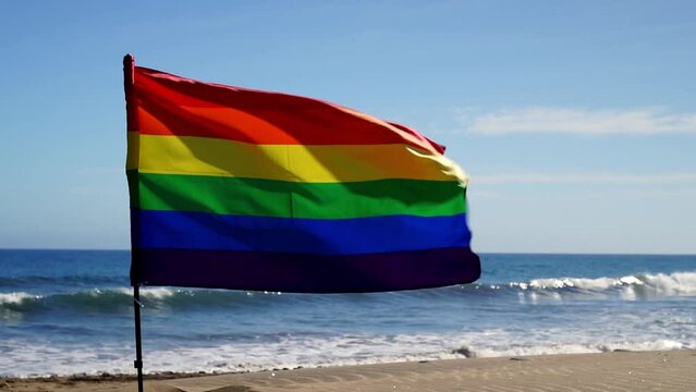 Bandiera arcobaleno sventolando all'aperto vicino al mare e con il cielo azzurro