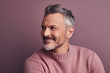 Fototapeta premium Portrait of a handsome middle-aged man in a pink sweater on a purple background.