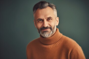 Portrait of a handsome mature man in a sweater on a gray background