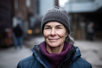 Portrait of smiling middle aged woman in winter jacket and hat standing outdoors
