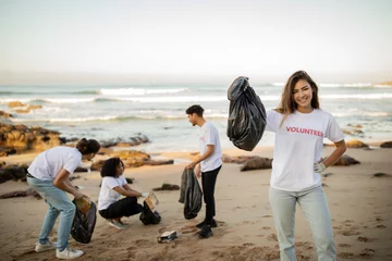 Zelfklevend Fotobehang Positive proud young asian lady volunteer with friends in gloves show garbage bag, clean up trash © Prostock-studio