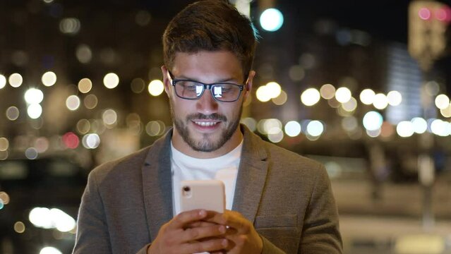 Lateral Dolly Businessman Wearing Glasses in City Center Street Thinking and Using Cell Phone Texting Scrolling Tapping. Young Handsome Breaded Man Using Smart Phone. Technology And Success Concept.  