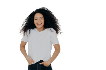 Half length shot of good looking smiling woman laughs at funny joke, has fun, keeps both hands in...