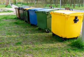 Black, blue, yellow, green garbage recycling bins on street in city. Separate waste, recycling environment concept. Segregate waste, sorting garbage. Colored trash cans with paper, glass, plastic