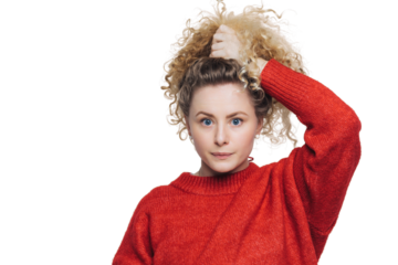 Portrait of woman with curly hair looks with confident and serious expression at camera, dressed in red sweater, isolated over white background. Beautiful female poses alone against white background