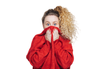 Frightened stunned female sees her phobia, covers face with collar of red sweater, stares at camera with scared look, isolated over white studio background. People, reaction and emotions concept