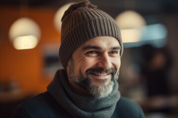 Portrait of smiling bearded man in beanie and scarf in cafe