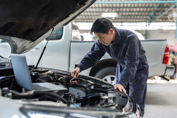 Fototapeta na wymiar Asian mechanic man using spanner tighten car battery at auto car garage service. Car repair and maintenance concept.