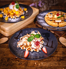 Delicious homemade waffles with fresh fruits, ice cream, meringue, strawberry, marshmallow, blueberry, mango, colorful candy, different toppings, banana, jam - sweet food