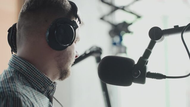 Handsome smiling radio host working in studio with microphone and headphones.