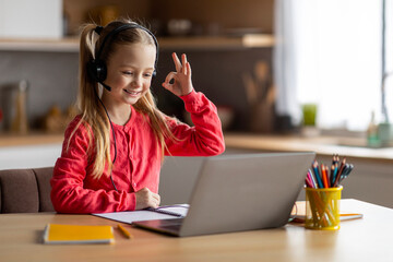 Fototapeta na wymiar Little Girl Having Video Call On Laptop At Home, Showing Ok Gesture