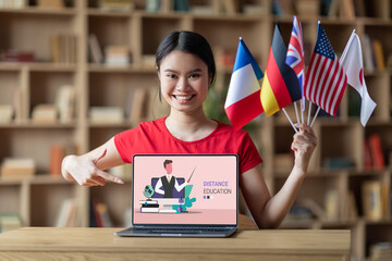 Happy asian lady student with international flags pointing at laptop
