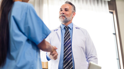 Surgeon medical and doctor people handshaking. Caucasian male doctor shaking hands with team on business cooperation agreement. healthcare and medicine