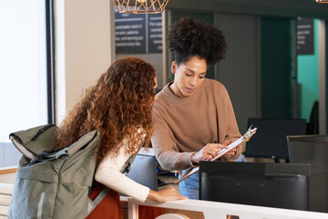 Young woman checks in at front desk, reception, hotel, college library admission