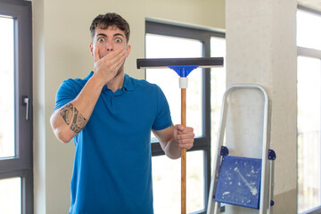 young handsome man covering mouth with a hand and shocked or surprised expression. windows washer...