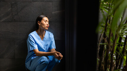 Hight contrast and drama concept. tired exhausted nurse or doctor woman sitting outside hospital. healthcare and medicine concept