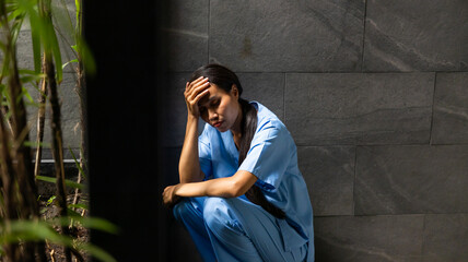 Hight contrast and drama concept. tired exhausted nurse or doctor woman sitting outside hospital....