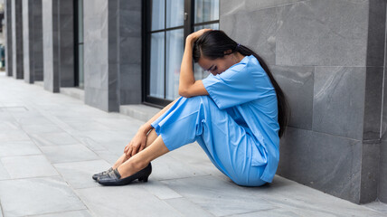 tired exhausted nurse or doctor woman sitting outside hospital