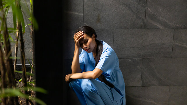 Hight contrast and drama concept. tired exhausted nurse or doctor woman sitting outside hospital. healthcare and medicine concept
