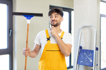 young handsome man smiling with a happy, confident expression with hand on chin. windows washer...