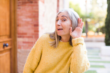senior retired pretty white hair woman looking happy, listening, trying to hear a secret...