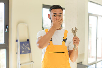 arab handsome man arab man covering mouth with a hand and shocked or surprised expression. handyman with a wrench