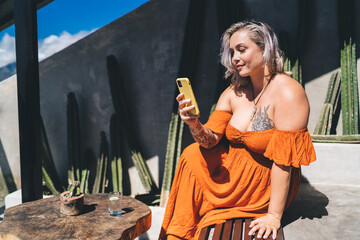 Obraz premium Young woman using smartphone while sitting in street cafe