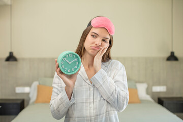 young pretty woman feeling bored, frustrated and sleepy after a tiresome. alarm clock concept