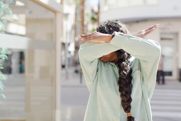 afro pretty black woman covering face with hand and putting other hand up front to stop camera,...