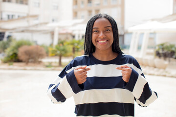 afro pretty black woman feeling happy, surprised and proud, pointing to self with an excited, amazed look