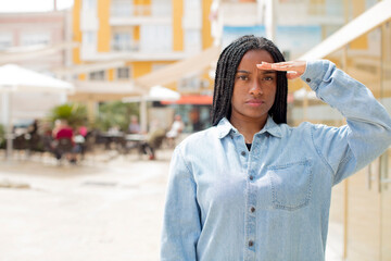 afro pretty black woman greeting the camera with a military salute in an act of honor and patriotism, showing respect