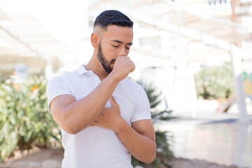 Fototapeta premium young handsome man feeling ill with a sore throat and flu symptoms, coughing with mouth covered