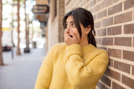 pretty woman covering mouth with hands with a shocked, surprised expression, keeping a secret or saying oops