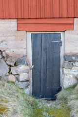 Black cellar door on traditional red cabin