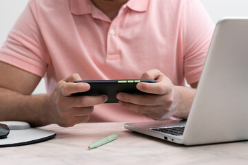 Close up of student playing with his cell phone while are taking a virtual class online