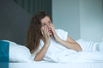 Sad upset depressed young woman suffer in bed in bedroom because of insomnia, tired girl with headache or hangover 