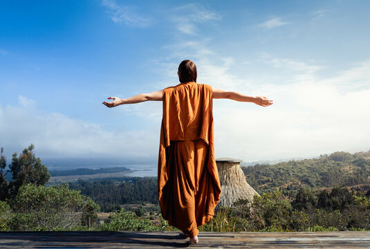 Mujer de espalda con brazos abiertos, contemplando la naturaleza y el cielo. 