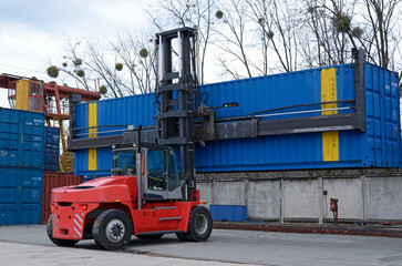 Electric forklift loader carrying cargo container in a container yard, railway station facilities. Kyiv, Ukraine