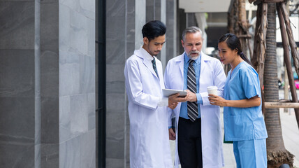 Professional medical staff people successful and teamwork concept. Diverse doctor and nurse walking and talking discussion on teblet together at hospital medical wellness center. Drink coffee