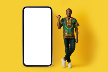 Cheerful handsome black man pointing at big smartphone, mockup