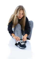 Portrait of pretty long hair girl tying shoelaces on her sneakers, isolated on white background....