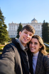 young couple visiting the royal palace in Madrid taking a selfie with their smartphones