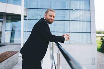 Confident businessman standing on street and looking at camera