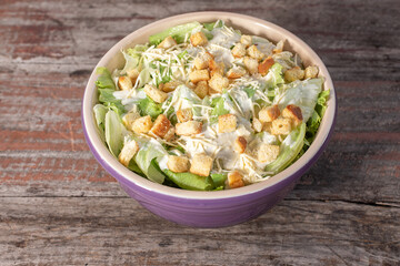 Delicious caesar salad in bowl on wooden background