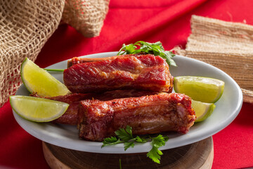 Roasted pork ribs served with lemon wedges.
