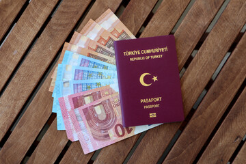 Turkish passport with Euro banknotes on wooden table photographed from above